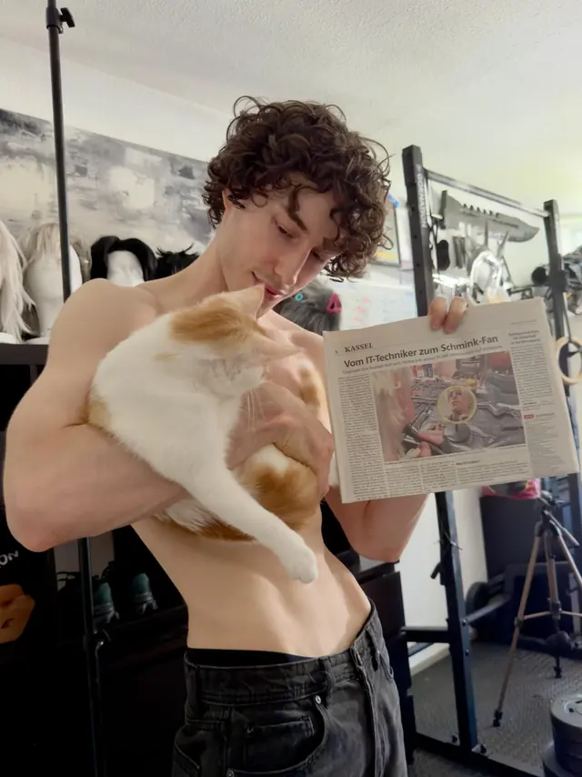 Ihor Kostash holding the printed HNA feature together with his cat in his workshop.