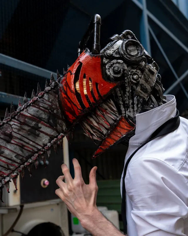 Close-up Chainsaw Man cosplay portrait featuring a handcrafted red and metallic chainsaw helmet.