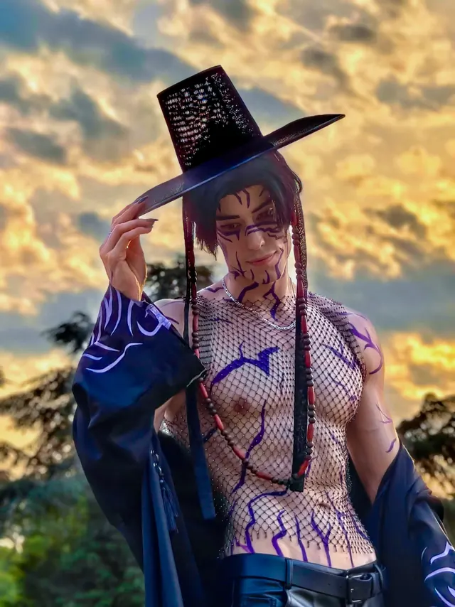 Close Jinu cosplay portrait at sunset while holding a wide black traditional hat.