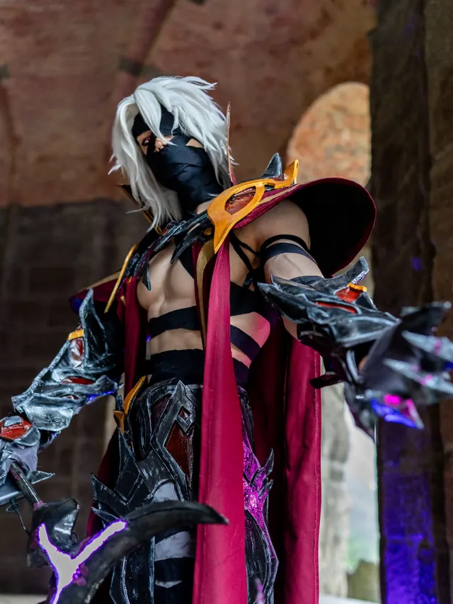 Rerir cosplay in black, red and gold armor with white hair and a dramatic fantasy weapon.
