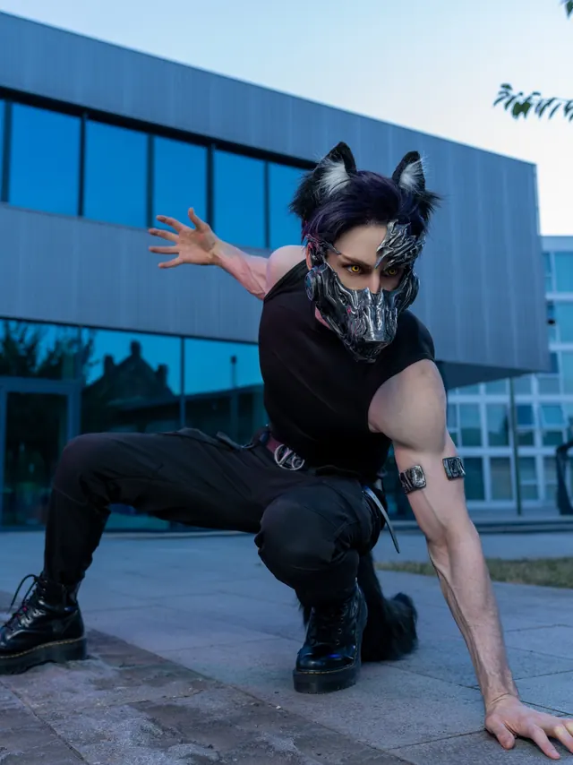 Valko cosplay in a crouched action pose with a metallic creature mask, black ears and dark tactical styling.