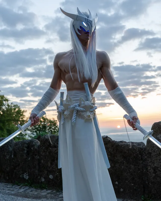 Yone cosplay at sunset with long white hair, a white mask and two glowing sword props.